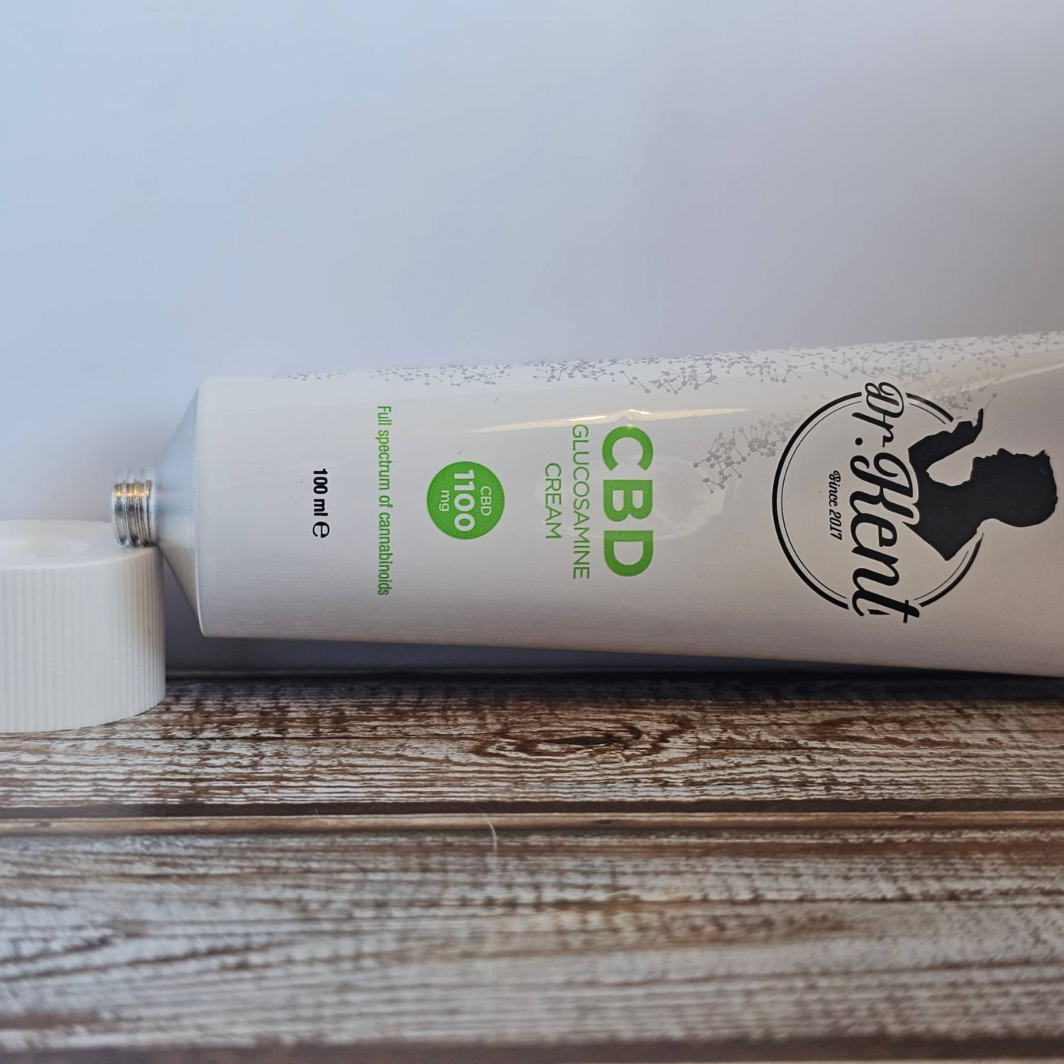 Et billed af en Dr. Kent creme liggende, på en træ bordplade med hvid baggrund.